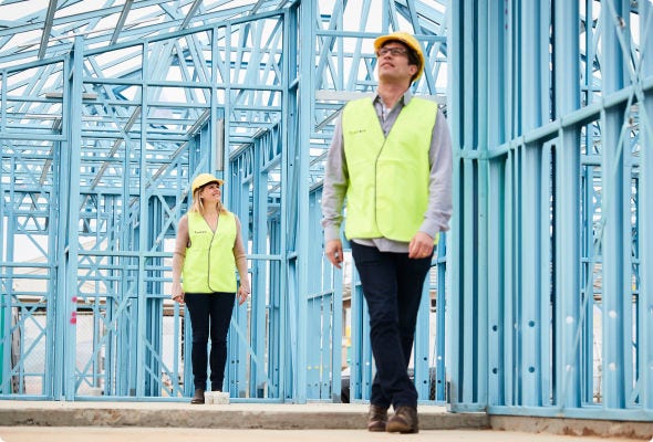 A building frame made from BlueScope's TRUECORE®  with two people carrying out a site inspection