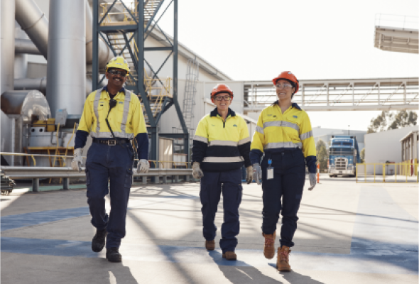 Three BlueScope employees outside manufacturing plant walking to camera