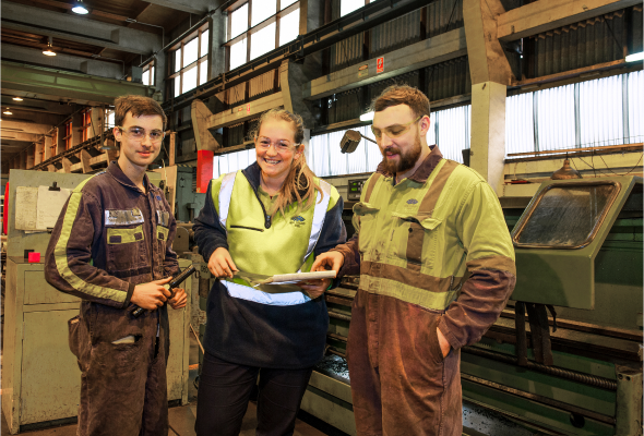 Two employees engaged in conversation, walking outside a manufacturing facility