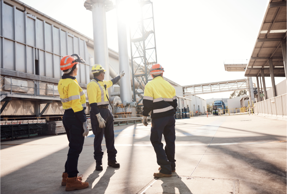 Three employees walking outside a manufacturing facility