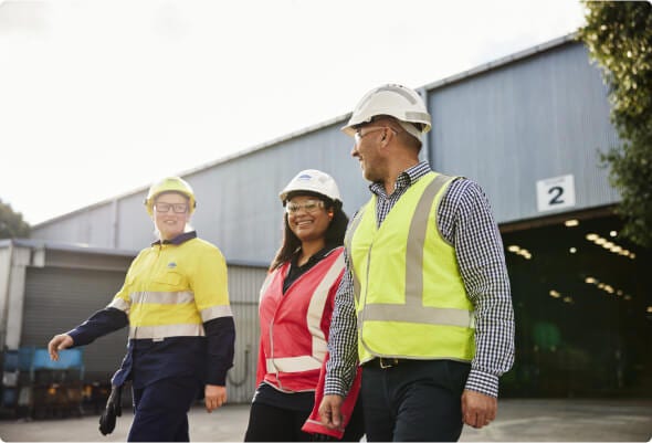 Three employees in high-visibility clothing walk away from a loading bay